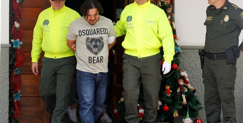 Juan Carlos Mesa Vallejo, also known as "Tom", is escorted by police officers during a press presentation at the Police headquarters in Medellin