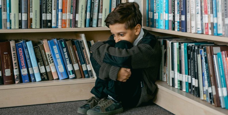 Niño triste en un rincón de un escaparate con libros