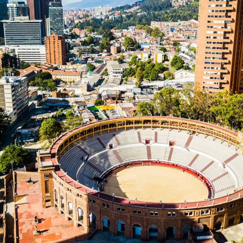 Una plaza de toros con dos torres de edificios detrás