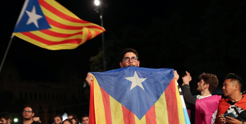 A man holds an Estelada (Catalan separatist flag) as people gather at Plaza Catalunya after voting ended for the banned independence referendum, in Barcelona