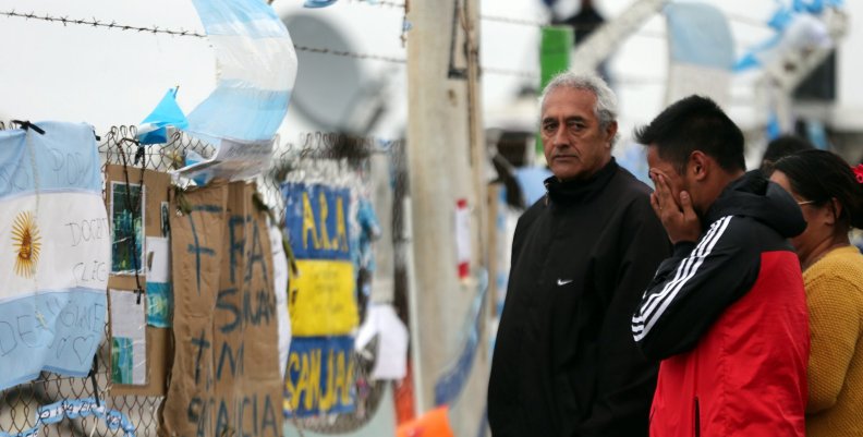 A man reacts in front of signs and messages in support of the 44 crew members of the missing at sea ARA San Juan submarine on a fence at an Argentine naval base in Mar del Plata