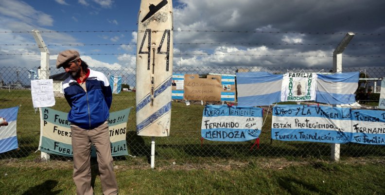 A man stands in front of signs in support of the missing crew members of the ARA San Juan submarine in Mar del Plata