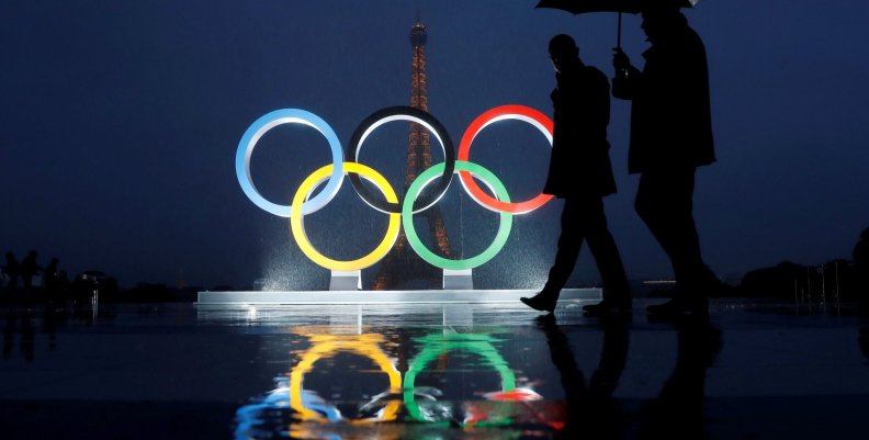 Men walk in the rain under an umbrella next to the Olympic rings after the IOC officially announced that Paris won the 2024 Olympic bid during a ceremony at the Trocadero square near the Eiffel Tower in Paris