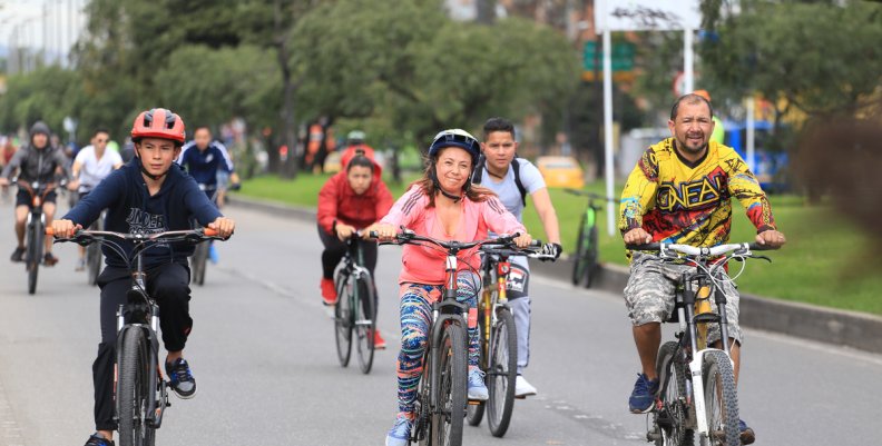 Tres personas montando bicicleta en la ciclovía de Bogotá