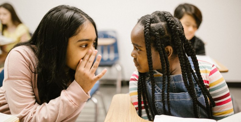 Dos niñas hablando en un salón de clases