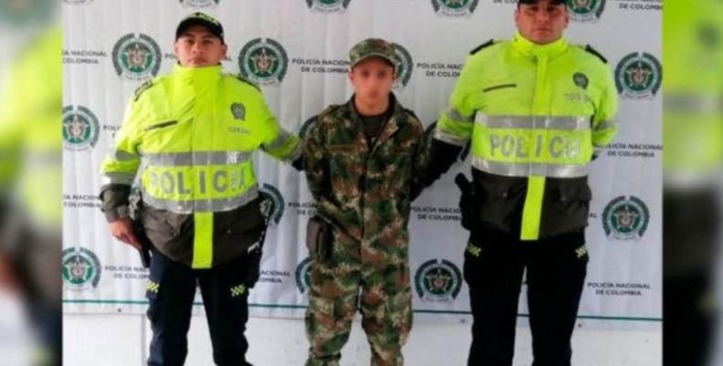 Dos oficiales de Policía, con un hombre capturado vestido con uniforme militar