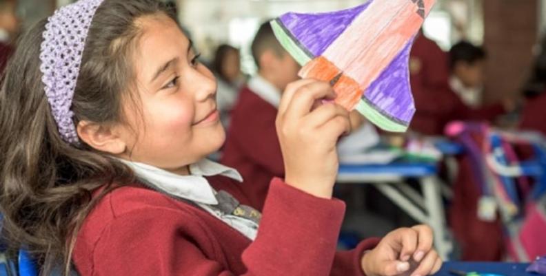 Niña jugando con una nave espacial de papel