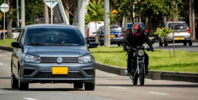 Un carro y una moto rodando en una calle