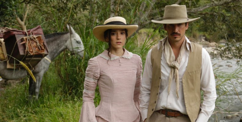 Un hombre y una mujer, vestidos con ropa blanca antigua. Atrás hay un caballo