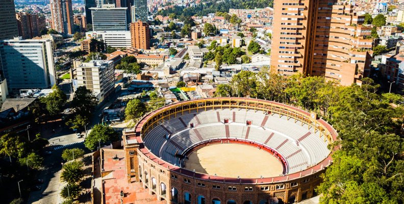 Hablemos Bogotá Una plaza de toros con dos torres de edificios detrás