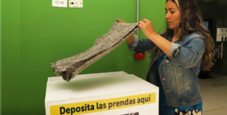 Mujer dobla una muda de ropa sobre una de las cajas dispuestas para las donaciones