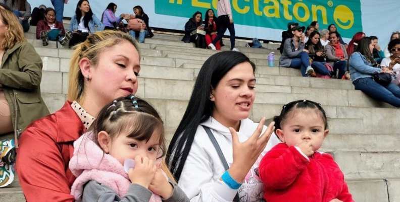 Dos mujeres con niñas alzadas en las rodillas estando en una escalera.