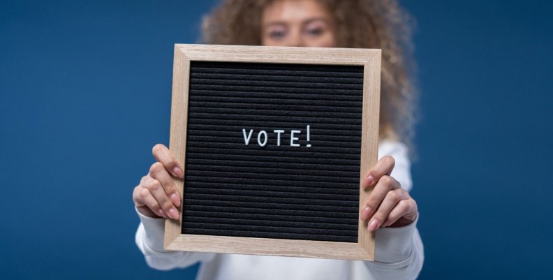 Niño sostiene un tablero con la palabra Voto