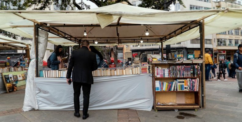 Hombre viendo un puesto con muchos libros en una Feria Popular de Bogotá