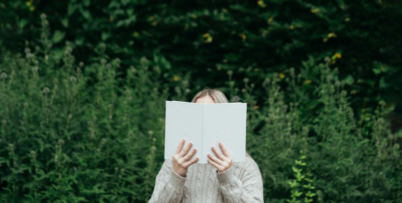 Mujer leyendo un libro en medio de un bosque