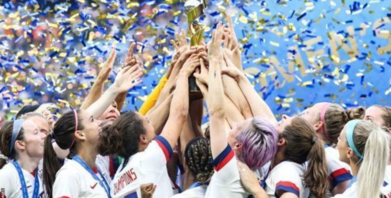 Mujeres de la Selección femenina de Estados Unidos alzan el trofeo del campeonato juntando sus manos.