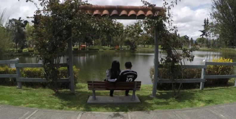 Un hombre y una mujer sentados frente al lago del Parque de los Novios 