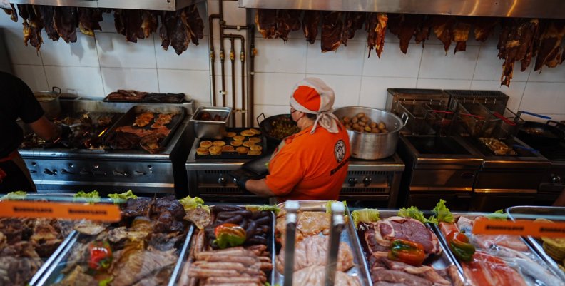 Cocina con una cocinera en el medio y rodeada de diversos ingredientes 