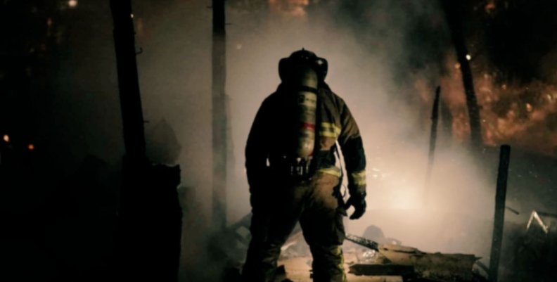 Bombero de espaldas frente a una conflagración recién apagada.