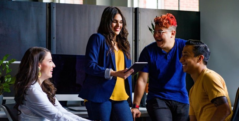 Compañeros y compañeras de trabajo jóvenes hablando durante un receso laboral