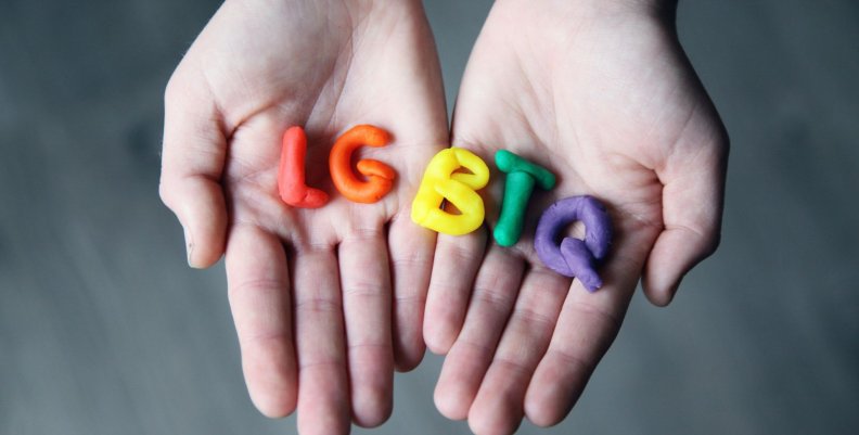 Manos con la palabra LGBTQ hecha de plastilina