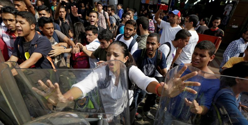 Opposition supporters clash with riot police in front of a courthouse in Caracas