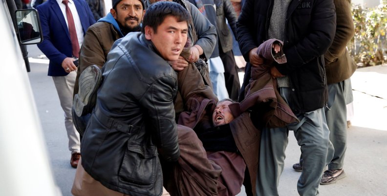 People carry a mourning man at a hospital after a suicide attack in Kabul