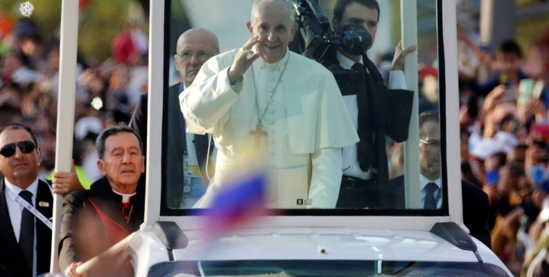 Pope Francis waves at the faithfuls as he travels in the popemobile through Bogota