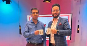 Dos hombres de traje levantando una tasa de café