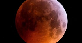 Foto de una luna llena toda de color rojo, sobre un fondo negro