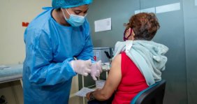 Mujer vacunando a otra mujer de la tercera edad