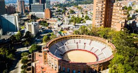 Una plaza de toros con dos torres de edificios detrás