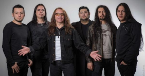 Cuatro hombres vestidos de negro al frente de un fondo gris
