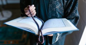Biblia con rosario sostenidas por unas manos de mujer 