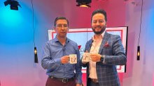 Dos hombres de traje levantando una tasa de café