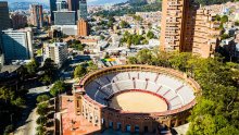 Una plaza de toros con dos torres de edificios detrás