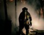 Bombero de espaldas frente a una conflagración recién apagada.