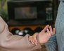 Una persona con saco gris le sostiene la mano a otra con saco café. 