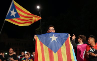 A man holds an Estelada (Catalan separatist flag) as people gather at Plaza Catalunya after voting ended for the banned independence referendum, in Barcelona