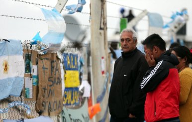 A man reacts in front of signs and messages in support of the 44 crew members of the missing at sea ARA San Juan submarine on a fence at an Argentine naval base in Mar del Plata