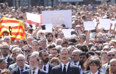 King Felipe of Spain sits between Prime Minister Mariano Rajoy and President of the Generalitat of Catalonia Carles Puigdemont as they observe a minute of silence in Placa de Catalunya in Barcelona