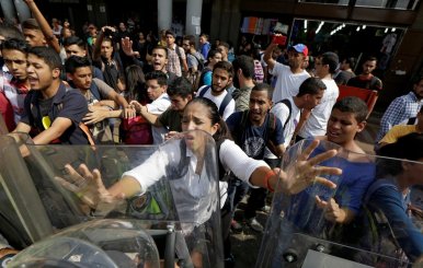 Opposition supporters clash with riot police in front of a courthouse in Caracas