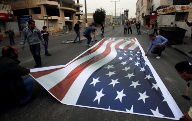 Palestinian demonstrators place on the ground a representation of a U.S. flag during a protest in the West Bank city of Bethlehem