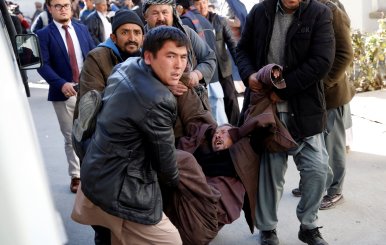 People carry a mourning man at a hospital after a suicide attack in Kabul