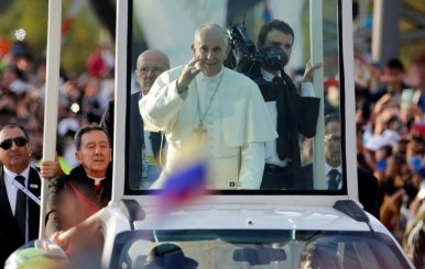 Pope Francis waves at the faithfuls as he travels in the popemobile through Bogota