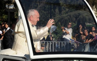 Pope Francis waves while driving through Santiago