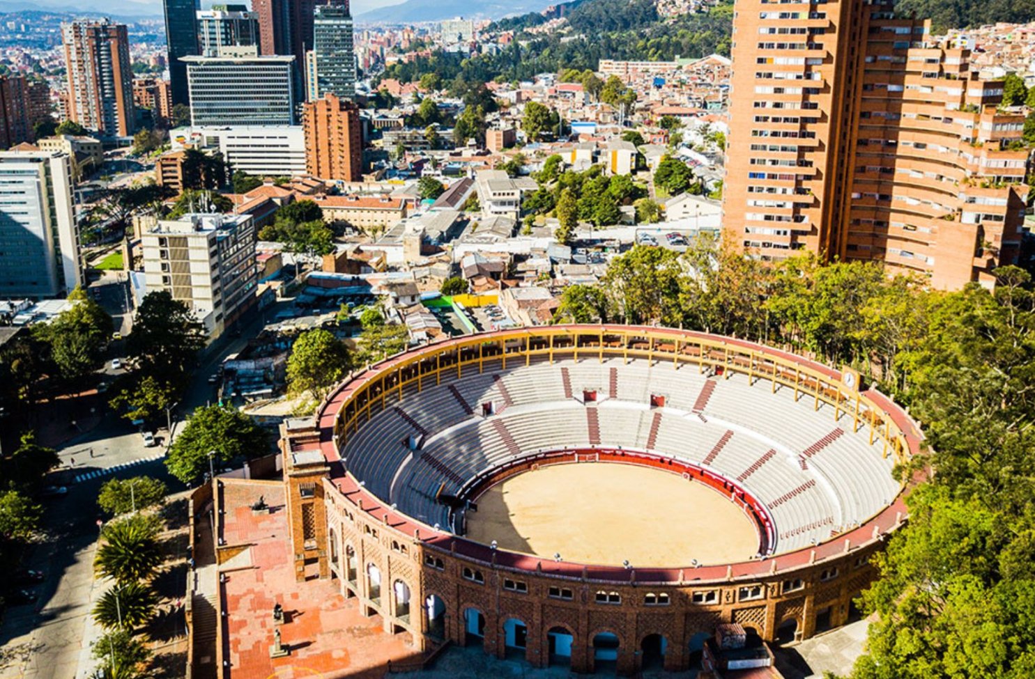 Una plaza de toros con dos torres de edificios detrás