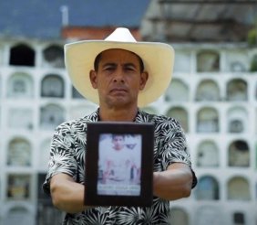 Hombre sosteniendo una foto de una persona frente a cámara