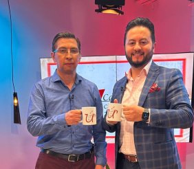Dos hombres de traje levantando una tasa de café