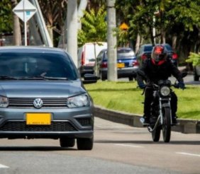 Un carro y una moto rodando en una calle